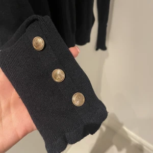 Stickad tröja med fina ärmar och krage - Fin tröja från HM med dekorerade ärmar och fin krage. Fint skick men inte oanvänd. 54% polyester,  20% polyester, 20% acrylic. Mörkt marinblå/svart 