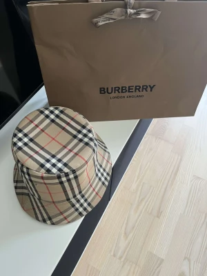 Burberry bucket hatt  - Säljer en burberry bucket hatt då den inte passar längre. Den är köpt på Köpenhamns flygplats,2022, och är endast använd ett fåtal gånger. Kvitto medföljer självfallet!  