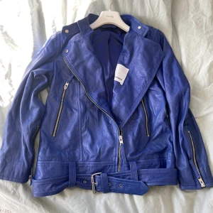 J.Lindeberg skinnjacka - J.Lindeberg  skinnjacka ”Maya Summer Leather Jacket”  i blå/lila färg. Väldigt fint skick, endast använd 1 gång. Säljer pga inte min stil längre. Nypris 4 999kr. Köparen står för frakten.