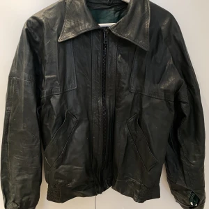 Mörkgrön skinnjacka  - Snygg retro skinnjacka i mörkgrönt. Köpt second hand. Snyggt grönt foder! Använd, men gott skick. 