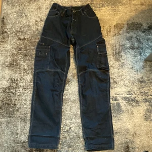 cargo byxor - snygga mörkblå cargo byxor, insydda i midjan! bra begagnat skick men lite slitage längst ned på ena benet men inget som syns i vanliga fall
