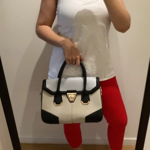 Handväska  - Stilren och snygg handväska från New Look.  Grå, beige och svart med gulddetaljer. Stor och rymlig.  Bredd 32cm.  Höjd 22cm.  Djup 14cm.  Djur- och rökfritt hem.  Rensar min walk-in-closet så kolla in mer å fynda. Samfraktar! 