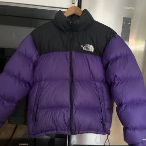 Northface puffer jacka - The Northface dunjacka i nyskick säljes. Andvänd 5 ggr max. Modell 1996 Retro Nuptse Jacket lila/svart. Stl Medium Säljes för 2500 kr, nypris 3700 kr.  Finns i Malmö, men kan skickas mot porto.