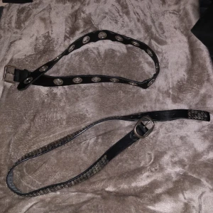 Svart bälte med detaljer - Säljer två stycken svarta bälten med coola detaljer! Osäker på var de är köpta! Jag använder de inte längre så därför säljer jag dem🙌🏼🙌🏼😝