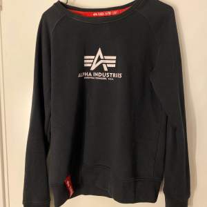 En svart sweatshirt i storlek M från Alpha Industries.