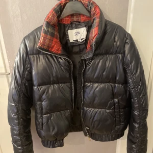 jacka från madlady - En jätte fin jacka från madlay som nästan är oanvänd, den är väldigt varm och skön och är i wtt mycket fint skick! längden på jackan är till naveln så den har en slags ”kroppad modell”. Den har också ett röd rutigt mönster innan för kragen. 