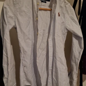 Ralph Lauren skjorta  - Randig Ralph Lauren skjorta i 100% bomull i modellen slim fit. Storlek 0 vilket morsvarar XS-XXS eller 32-34. 