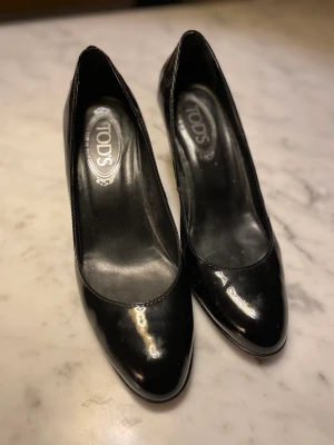 Tod’s pumps svarta  - Dax för dessa underbart snygga tod’s skor att dansa vidare! Inköpta i London för drygt 10 år sedan. Liten reva på klacken men annars i mkt bra skick! Svarta, glossiga, strlk 37.5. 