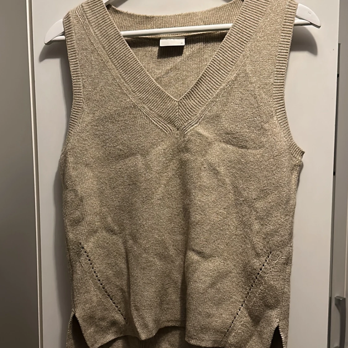 En stikad beigeväst med v-ringning