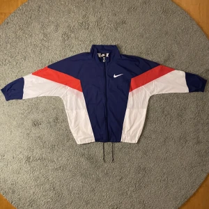 Tunn Nike Vindjacka - En vintage Vindjacka jag säljer pga vuxit ur den, väldigt bra skick och ganska tunn, jag har köpt den för 750kr och har hållit den i bra skick så mitt pris är 400kr. (Pris kan diskuteras vid snabb affär) Finns att köpa i Uppsala men kan också frakta