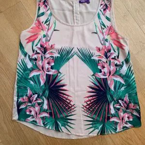 Cremefärgat linne med läckert blommönster på framsidan. Enfärgad baksida. 100% polyester. Svalt och skönt på sommaren. 