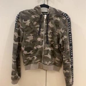 Hoodie, kamouflagemönstrad. S - Kortare hoodie i kamouflagemönster. Storlek S.