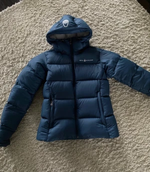 Sail racing jacka i nyskick! - Varm vinterjacka från Sail racing   modell: Sail racing Cloud down Hood   Storlek: Xs  Nypris 4000kr  Använd fåtal gånger så i fint skick!