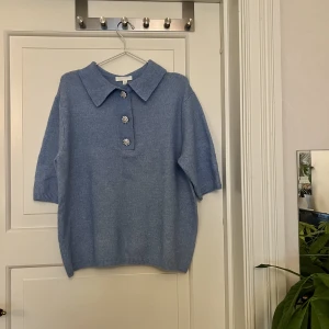 Blå stickad tshirt🤍 - Blå stickad tshirt med krage och dekorativa knappar. Från H&M, storlek S. Använd en gång. Finns två små fläckar som kanppt syns, en vid bröstet samt en vid axeln, skickar bild vid önskemål. Kan mötas upp i Göteborg eller skicka, köparen står för frakt.