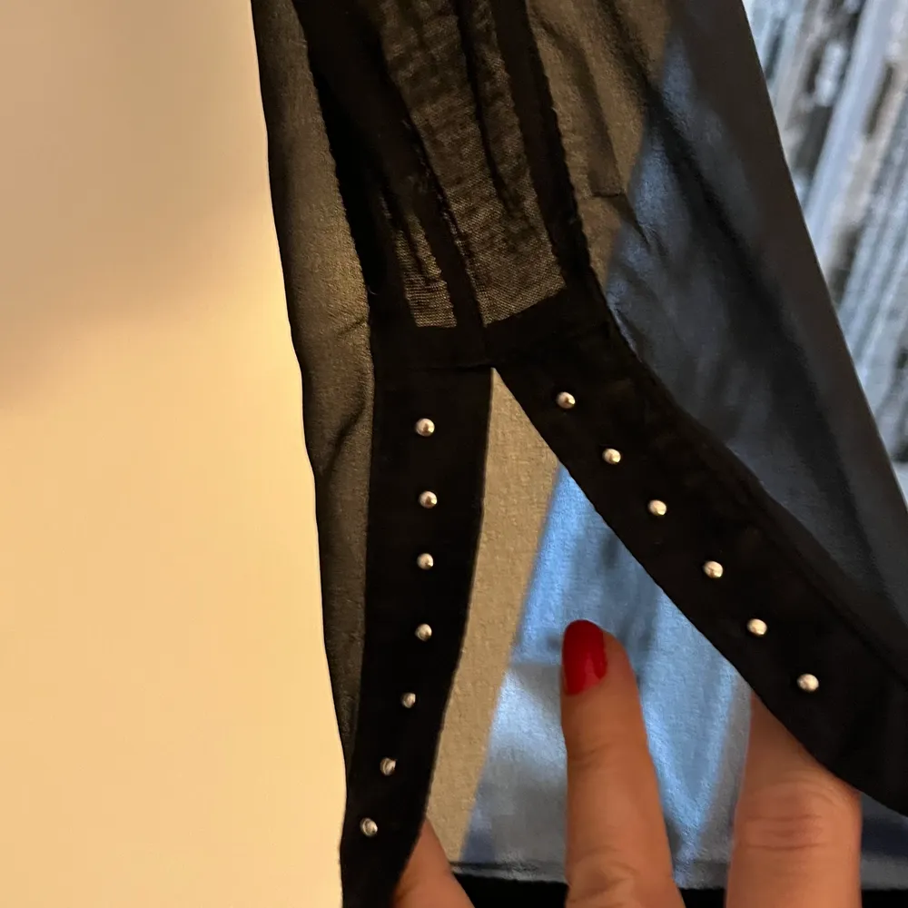 Långärmad topp i skirt material med nitar som dekoration. Sprund i ärmsluten. . Yläosat.