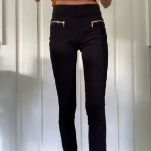 Svarta kostymbyxor  - Svart spets längst benen, swipe för bild, guldiga dragkedjor fram. Från amisu, strl 36