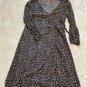 Djuptryck, klänning  - En svart, brun lång Wrap dress som  går att går att knyta vit midjan. 