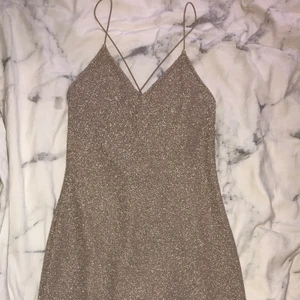 Glittrig klänning - Nyskick klänning med glitter och öppen rygg med snören. Stl:xs passar mig som är en s oxå. 