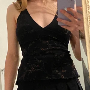 Top  - Strechig svart top med guldigt blommönster 