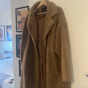 Teddykappa fodrad - Varm och skön teddykappa med foder från Lager 157. I storlek L/XL och slutar nedanför knäna på mig som är 160, har två sidfickor och stängs med knappar.