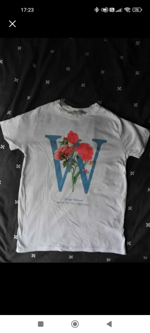 Enkel och elegant blus med korta ärmar. - Enkel vit kortärmad blus med stort tryck framtill.  Ny och oanvänd.  Blusen är tunn med ett halt men behagligt material.