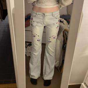 Ljusa lågmidjade jeans med blommor på. Långa!  Supersnygga men kommer aldrig till användning:( Midjemåttet är 80cm 