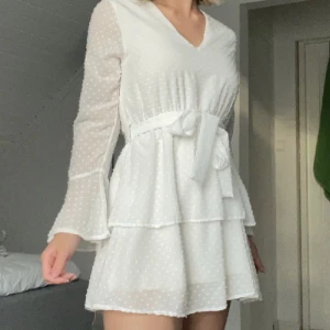 Vit klänning - Vit kort klänning med små prickar i tyget från Madlady. Perfekt till studenten! Knytningen kan göras antingen fram eller bak. Aldrig använd! 