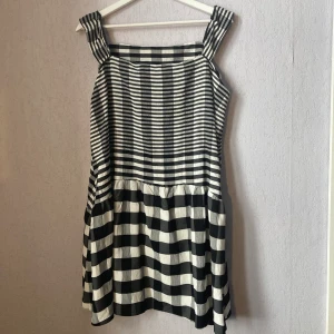 Rutig klänning - Svart och vitrutig klänning av okänt märke, omsydd vid axlar. Vid passform. Lätt och bekvämt material. Inga defekter, är i gott skick. 