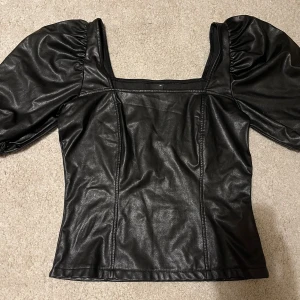 Festtopp med puffaxlar  - En superfin ”fest” topp från Gina Tricot i läderimitation med fyrkantig ringning och puffiga axlar. Så himla cool o framhäver kroppen så snyggt 😍😍i strl XS men passar även en S! 