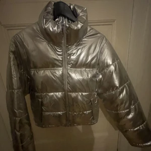 Dunjacka Silvrig ⚡️💋 - Ball silvrig dunjacka från Gina Tricot, har användigt jackan max 1 gång. Jättefint skick förutom att lappen i nacken är sönder, men inget som syns utanpå. Kan skicka fler bilder vid behov😊💖