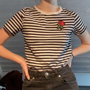 Söt t-shirt - Söt randig t-shirt med en ros på. Vet inte storleken men mellan xs-en liten medium skulle jag gissa :) 45kr frakt om man köper genom mig och inte köp nu :)