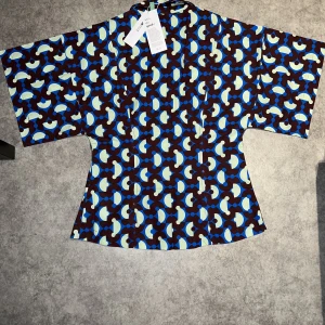 Retro skjorta  - Helt ny skjorta med prislappen på, har testat en gång men fel storlek. Gul, brun och blå skjorta med mönster. Storlek M men lite tajt runt midjan, gjord på bomull.   Passar bra till tema partyn och varma sommardagar, materialet känns breathable. 
