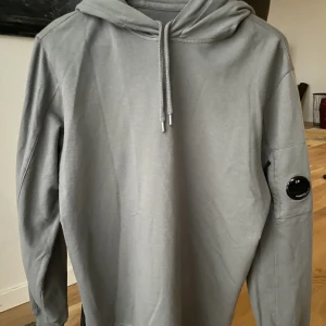 C.P. Company Hoodie - Säljer denna snygga mörkgrå C.P. Company Hoodien. Stl M Perfekt julklapp🎁  Tag & prislapp finns bild 2 samt kvitto Cond: 9/10 Den är i princip nyskick men jag har använt den några gånger så vill inte säga 10/10. Bara att meddela vid intresse eller frågor!