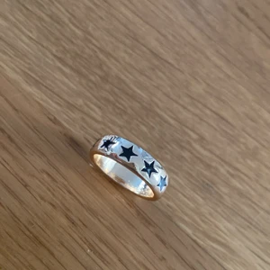 Ring - En guldig ring med svarta stjärnor på. 1 andvänd gång