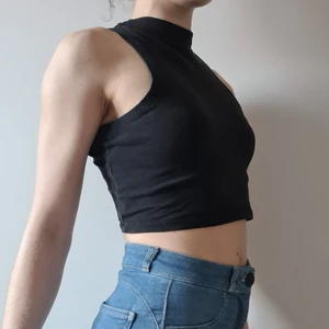 Svart croptop med polokrage - Skön, svart, croptop med polokrage. Ärmlöst linne.ä av märket Atmosphere.