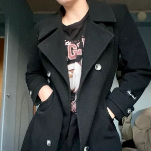 Svart, lång ullkappa - Säljer min svarta ull kappa eftersom den börjar bli för liten över axlarna. Den går mig som är 174 cm lång till vaden. Något sliten, men fantastisk kvalitet!