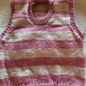 Hemmagjord stickad väst - En hemmagjord stickad väst, randig med färgerna rosa och beige. Passar ungefär M/L, även S om man vill ha den lite oversize. Det är acrylgarn. 