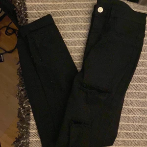 Jeans med hål i. - Säljer ett par tajta svarta jeans med hål längst benen. Använda endast en gång!