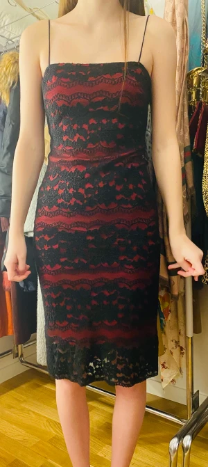 Stretch klänning stl 32-36 (xxs-s) - Snygg och skön klänning med stretch tyg som kramar kroppen. Undertill är det ett hallonröd slät tyg och ovanpå är det svart spets. Tunna ’snöre’ axelband.
