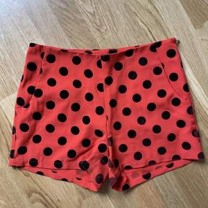 Shorts in orang with black dots in velvet. With pockets and invisible zipper. Perfect to use with tights.