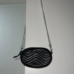 Svart liten väska  - Oanvänd Svart liten axelväska, kan även användas som midjeväska , det ingår ett svart läder band om man vill använda den som midjeväska.