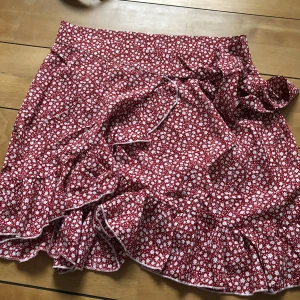 Röd blommig kjol - Röd blommig kjol, aldrig använd! Frakt tillkommer på 40kr:)