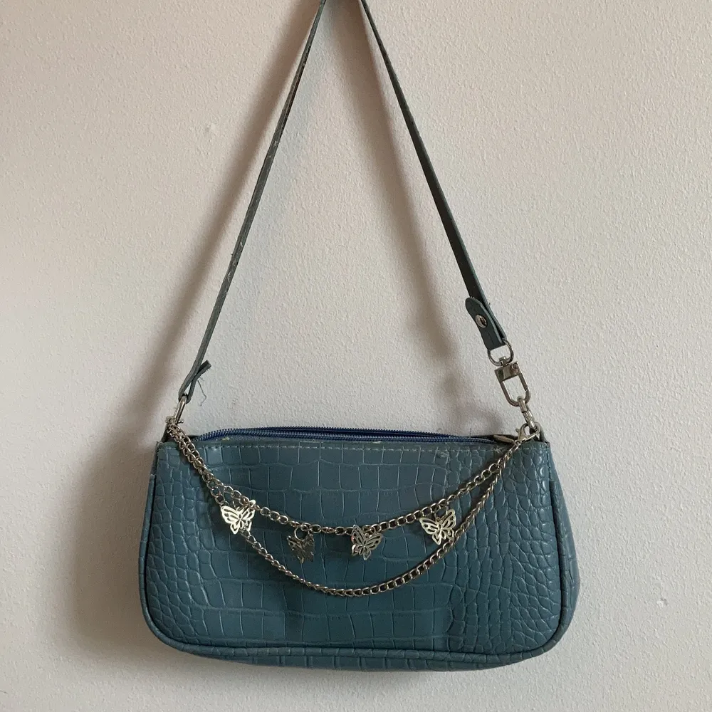 Jag säljer en blå väska som har en kedja med fjärilar på. den är nog använd 1-2 gånger har inga skador förutom att kedjan inte sitter fast helt längst bak men det går nog att fixa:) . Väskor.