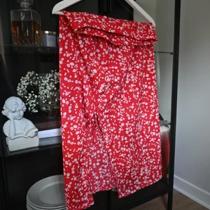 Blommig kjol i rött med slits  - En så vacker röd blommig kjol med vita blommor! Slits med dragsko som går att justera samt en dragkedja vid sidan.  Storlek M men passar mer en S.  Frakt ingår i priset!!🚚📦