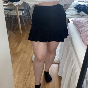 Svart minikjol - Svart minikjol med knappdetaljer. Storlek 38