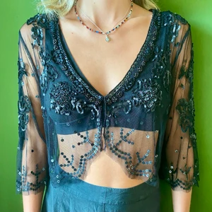 Svart bolero med paljetter - Svart bolero i meshtyg med paljetter.