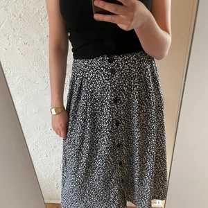 Långkjol Monki - En svart/marinblå långkjol med vita små blommor på. Knappar och fickor framtill.  Märke/Monki. Strl Xs. Mjukt och stretchigt material. Köparen står för frakten. 