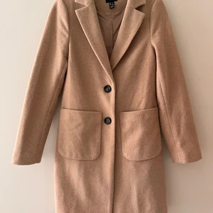 Kamelfärgad höstkappa - Kamelfärgad/beige höstkappa från New Look, köpt från Asos. Strl 32 men mer som 34. Går ungefär till knäna på mig som är 170cm. 