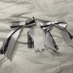 Handgjorda hårrosetter  - Handgjorda hårrosetter i vit satin och svart spets, dekorerade med ett hjärta (plast). Rosetterna kommer i par och fästs i håret mes hjälp av klämmorna på baksidan! Fint i twintails och andra håruppsättningar! 💕 (DMa & betala med swish för billigare frakt