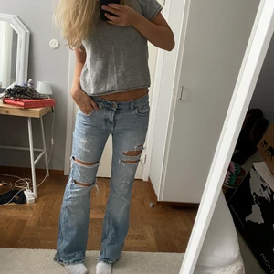 Slitna lågmidjade jeans  - Slitna, raka jeans köpta secondhand. Hål under bakfickorna men går att sy ihop (kan fixa vid extra betalning). Jag är 170 Säljer pga flytt utomlands, går att få paketpris vid köp av fler plagg. Frakt ingår inte